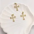 Vista dettagliata di tre ciondoli a croce in oro 18K con zirconi in un vassoio a conchiglia - Croce in zircone bianco pavé