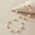 Eleganti orecchini a cerchio dorati con perle bianche su sfondo beige minimalista - 8 Perle Cerchio Dorato / Oro