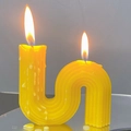Modern S-shaped ribbed scented candle in bright yellow with twin flames burning - Large S-Shape / 10x10x3cm Box / Yellow
