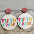 Macro detail of wooden Fifth Grade teacher earrings with colorful lettering and steel pins - Fifth Grade