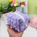 Handgehaltene hellviolette Beuteltasche mit gesteppter Blasenstruktur und Reißverschluss - Violett