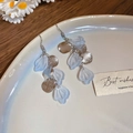 Dettaglio di orecchini lunghi pendenti argentati con petali blu su vassoio ceramico - Argento-Blu