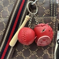 Detailed view of mini red baseball glove, bat, and ball keychain on a patterned bag strap - All Red Baseball Set