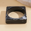 Macro view of geometric square resin bangle featuring black and white marble patterns - Black