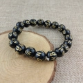 Men's black obsidian bead bracelet with golden mantra engravings on wood background - 10mm Pure Six-Syllable Mantra