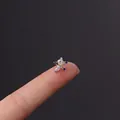 Delicate star cartilage earring with blue zircon in stainless steel held by fingers - Blue Star Style (3#S)
