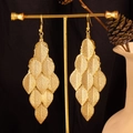 Detailed close-up of golden multi-layered leaf tassel earrings on a display stand - Textured Leaf / Gold