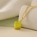 Macro view of yellow enamel dice pendant with golden heart pips on a chain - Green