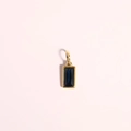 Golden rectangular charm with deep blue zircon stone on a soft pink background - September Birthstone Pendant / Gold