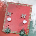 Christmas earring set with glittery green snowflake, snow globe, and bow studs on red card - 3-Pair Bow & Snowflake Set (H-150)