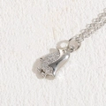 Collana con ciondolo a pinguino d'argento e zirconi su uno sfondo beige testurizzato - Pinguino Argentato