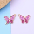 Dettaglio macro di ciondoli a farfalla con glitter rosa, bordi dorati e doppi ganci - Anello Singolo / Rosa & Rosa