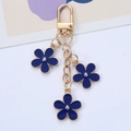 Detail of navy blue enamel flower keychain with gold-tone hooks and triple pendants - Sapphire Blue