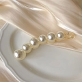 Detail van gele acryl bananenklem met parels op een elegante zijden achtergrond - Klassieke Parel Banaan Clip