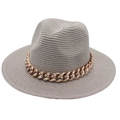 Détail d'un chapeau fedora en paille grise avec une grosse chaîne en métal doré - Chapeau de Paille à Bord Plat / Gris