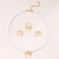Flat lay of vintage bow jewelry set featuring pearl necklace, earrings and ring in gold finish - Gold Bow 3-Piece Set (07)
