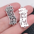 Antique silver music note pendant on hand showing size for DIY jewelry making - Dual Link Note (28x12mm-2.1g)