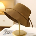 Detailed texture of cotton bucket hat featuring a metal tag and elegant rear bow tie - Camel