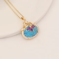 Collana dorata con pendente in pietra blu ovale e dettagli floreali in zircone rosso - Blu lago