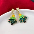 Detailaufnahme grüner Weihnachtsbaum-Ohrringe mit Goldsternen auf weißem Keramikteller - Stern Weihnachtsbaum