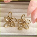 Dettaglio di orecchini a fiore di cristallo con petali dorati e strass incastonati - Orecchini a Fiore Trasparente - Bianco