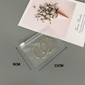 Close-up of 9x11cm transparent PVC jewelry storage bag holding golden hoop earrings - 25 Silk 11*9cm (100 Pcs)