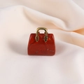 Detail view of mini red gemstone handbag charm with gold handle on beige fabric - Red Jasper