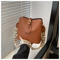 Detail of brown litchi pattern bucket bag featuring a wide patterned strap and gold hardware - Brown