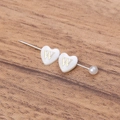 Creamy heart shell bead with golden letter W and pearl accent on wooden background - Letter W