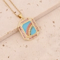 Macro shot of 18K gold pendant featuring blue enamel rainbow and pink gemstone border - Rainbow Rectangle