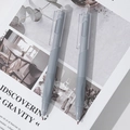 Dettaglio di due penne a scatto grigie con punte in cera su un libro dal design sobrio - Pezzo Singolo / Grigio