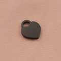 Dettaglio di un ciondolo a cuore nero con anello d'argento su tessuto strutturato rosa - Nero