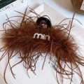 Detail of a brown feather hair claw clip featuring a rhinestone logo on black resin - Rhinestone Letter Style / Brown