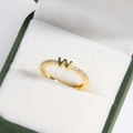 Macro shot of 18k gold plated letter W ring with diamonds in a green velvet jewelry box - Letter W Gold