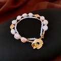 Détail du bracelet double couche avec perles baroques et fermoir OT doré sur tissu noir - Bracelet avec Boucle OT en Métal et Perles Baroques