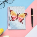 Close-up of a spiral notebook with a colorful glitter butterfly cover and pink coil - Butterfly