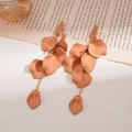 Detail of terracotta petal tassel earrings on vintage book page with golden chain links - Peach Pink