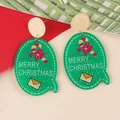 Macro detail of acrylic Christmas earrings with candy cane pattern and Merry Christmas text - Green Oval