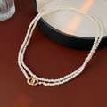 Detail einer doppelreihigen Perlenkette mit einem goldenen, ineinandergreifenden Verschluss - Gold-Weiß-4mm