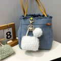 Close-up of blue denim mini bag keychain with white plush ball and yellow leather strap - White