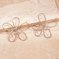 Detail of silver twisted metal flower earrings on a textured cream stone surface - Stainless Steel Post - Silver