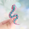Snake brooch with pink and blue rhinestones set on a metallic base held by hand - Rose Pink