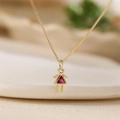 Macro detail of gold necklace featuring a cute girl pendant with pink and clear crystals - July Rose Red