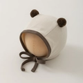 Detail of baby ear protection hat with brown pom-poms and ribbed cotton texture - One Size (35-45cm) / Beige