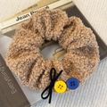 Detail of brown faux fur hair scrunchie with bow and colorful buttons on a book - Light Coffee