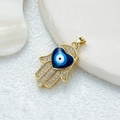 Goldener Hamsa-Anhänger mit blauem Herz und funkelnden Zirkonsteinen auf weißem Tablett - D3507JN Anhänger 14