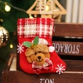 Detail eines roten Weihnachtsstrumpfs mit Plüschbär, Pailletten und festlichen Schneeflocken - Karierter Bär