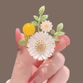Elegant white daisy alloy brooch with green leaves and yellow bead in a hand-held view - 363# Daisy