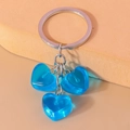 Detalle de tres corazones de resina azul traslúcida en un llavero de metal plateado - Azul