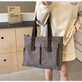 Detail der grauen Segeltuchtasche mit großen Fronttaschen und dunkelbraunen Griffen - Grau